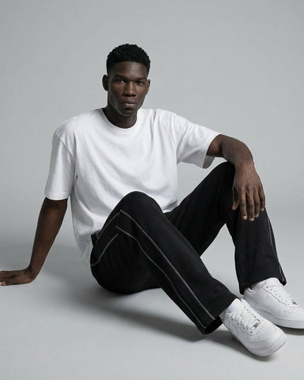 Model sitting while wearing Contrast-Stitched Fleece Sweatpants