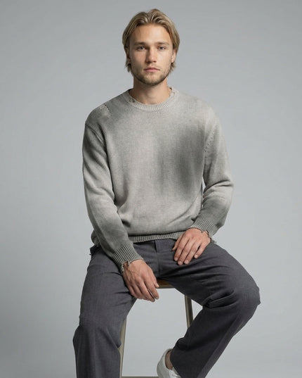 Model sitting while wearing Sun Fade Distressed Ripped Crewneck sweater